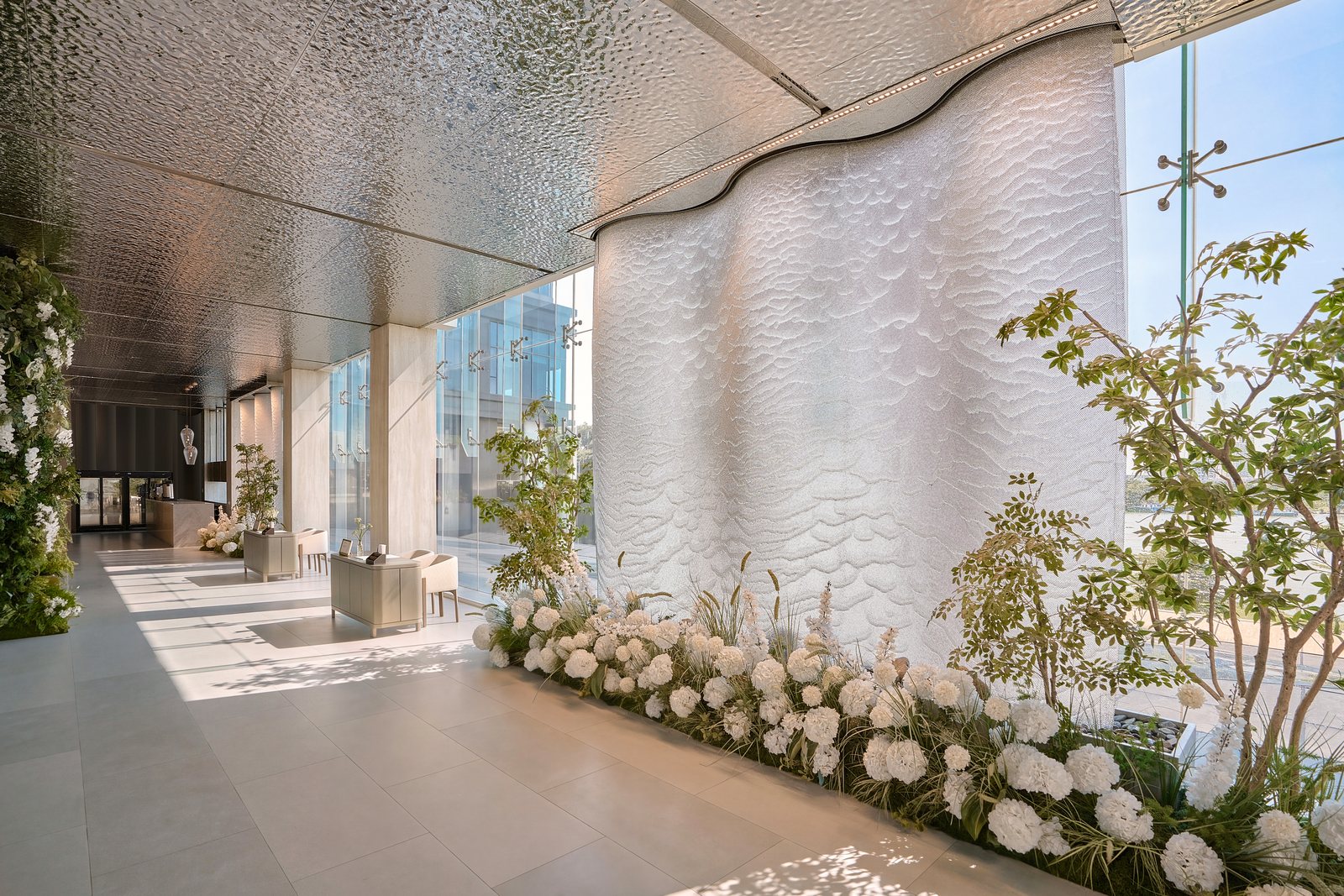 Arrival lobby with sculpted wall and white flowers, The Chapel at Saigon