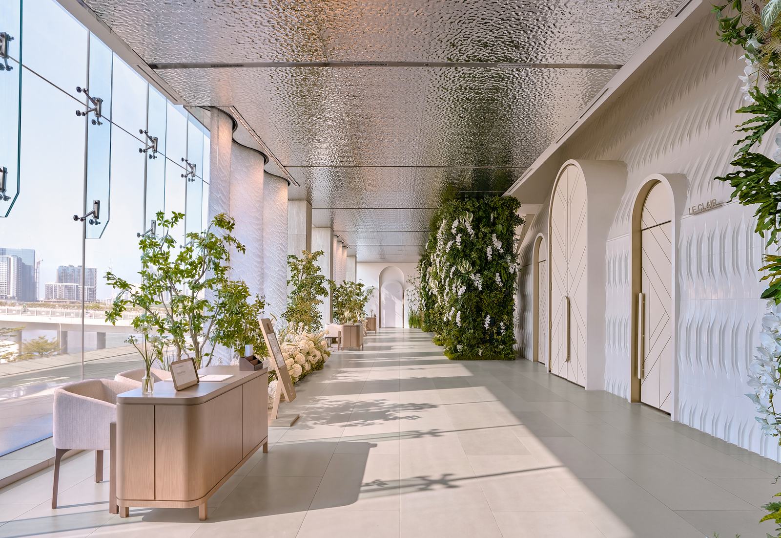 Sunlit entrance gallery at The Chapel at Saigon, with a metal ceiling, living green wall, arched doors and glass facing the river. A wedding venue developed by WEDDINGBOOK